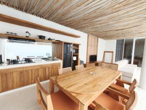 a kitchen and dining room with a wooden table and chairs at Villa Melody Uluwatu by LODGELINK BALI in Badung