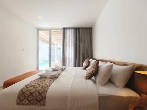 a bedroom with a large white bed with a window at Villa Melody Uluwatu by LODGELINK BALI in Badung