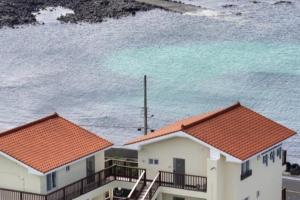 a group of houses with the ocean in the background at Jeju Bahama Pension in Jeju