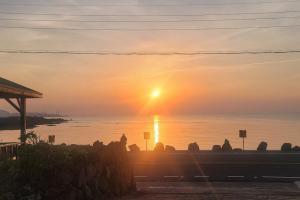 a sunset over a body of water with the sun setting at Jeju Bahama Pension in Jeju