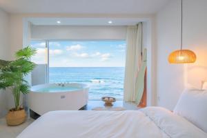 a bedroom with a tub and a view of the ocean at Gangneung The View Pension in Gangneung