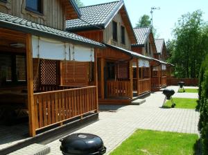 a row of wooden houses with a grill in a yard at CYKADY domki letniskowe Okuninka in Okuninka +20 photos
