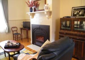 a living room with a fireplace and a couch at Kookaburra Cottage in Castlemaine