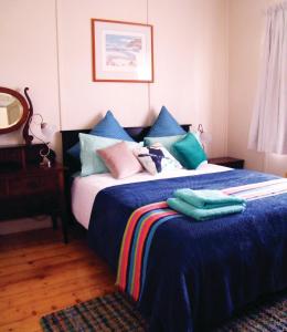 a bedroom with a bed with blue sheets and pillows at Kookaburra Cottage in Castlemaine