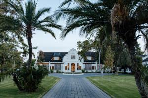 an exterior view of a white house with palm trees at Uitsig Boutique Hotel in Welkom
