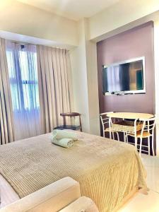 a bedroom with a bed and a table and a television at Nico's Studio Condo in Cebu City