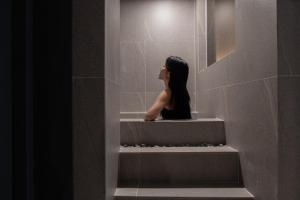 a woman sitting on a shelf in a bathroom at Brown Dot Hotel Incheon Bupyeong in Incheon