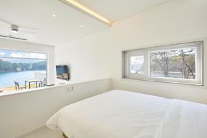 a white bedroom with a bed and a window at Geoje The Shine Pool Villa in Geoje