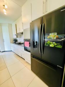 a kitchen with a black refrigerator with vegetables on it at Que Self Catering Apartments - Block7 in Gaborone