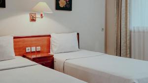a hotel room with two beds and a night stand at Royal Brongto Hotel in Yogyakarta