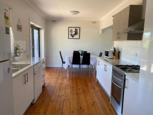 a kitchen with white cabinets and a table with chairs at Private 3Bed Home with Large Deck Central Location in Eaglehawk