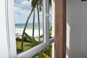 an open window with a view of the beach at Tremendo Beachfront Apartment in Kiwengwa +24 photos