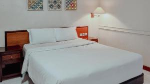 a bedroom with a white bed with a wooden headboard at Royal Brongto Hotel in Yogyakarta