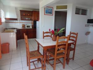 a kitchen with a wooden table and chairs and a kitchen with a kitchen at Gîtes Dardanelle in Bouillante