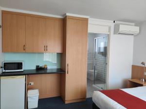 a bedroom with a bed and a kitchen with a microwave at Barclay Motor Inn in Devonport