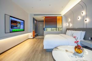 a hotel room with a bed and a tv at Ibis Styles Nantong North High-tech Zone in Nantong