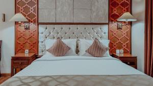 a bedroom with a large white bed with two lamps at Royal Brongto Hotel in Yogyakarta