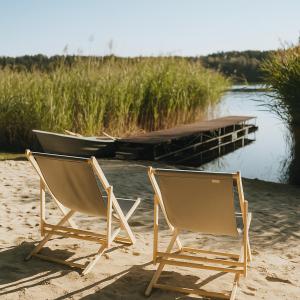 two chairs sitting on a beach next to a boat at Pokoje nad Dymnem in Koczała