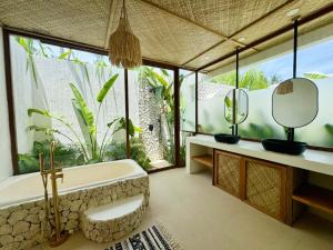 a bathroom with a tub and a large window at Baiana Beach Villas in General Luna