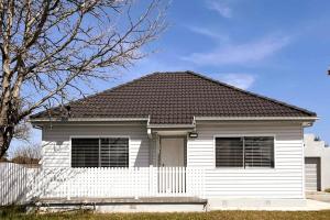 a white house with a black roof at Sam's Cottage on Hennessey in Moe