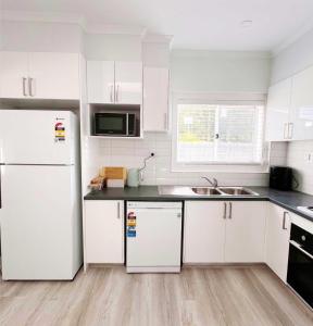 a kitchen with white cabinets and a white refrigerator at Sam's Cottage on Hennessey in Moe
