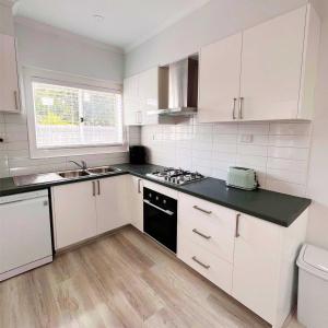 a kitchen with white cabinets and a black counter top at Sam's Cottage on Hennessey in Moe +10 photos
