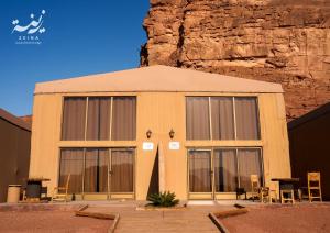 a building with large windows in front of a mountain at Zeina Desert Lodge in Wadi Rum