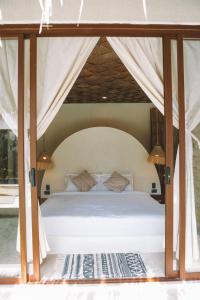 a bedroom with a white bed with a canopy at Baiana Beach Villas in General Luna