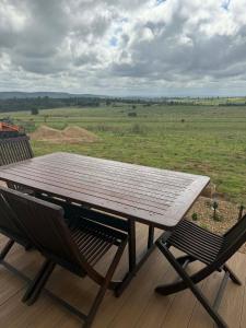 a table and chairs on a deck with a view of a field at Country Charm Cabins 2 Bedroom Tiny Home in Coolabunia +12 photos