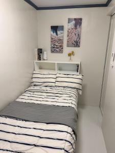 a small bedroom with a bed with striped sheets at DG Luxe Suites - Cabanatuan in Bangad