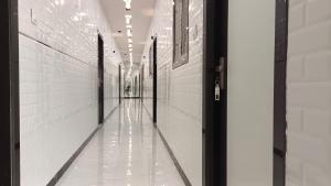 an empty hallway with white walls and a door at Hotel kingspalace and Dormitory in Vapi