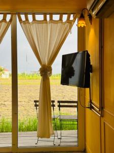 a window with a curtain and a tv on a porch at Padi Box Homestay in Sekinchan +17 photos