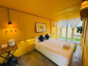 a yellow bedroom with a bed and a window at Padi Box Homestay in Sekinchan