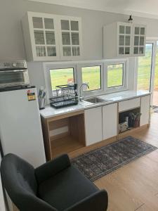 a kitchen with a refrigerator and a sink and a chair at Country Charm Cabins 2 Bedroom Tiny Home in Coolabunia