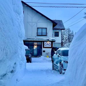 a car parked in front of a building covered in snow at Myoko House in Myoko