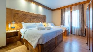 a bedroom with two beds and a large wooden headboard at Hotel Oasi in San Vito di Cadore