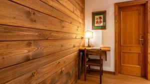 a wooden wall in a room with a desk and a lamp at Hotel Oasi in San Vito di Cadore