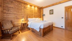 a bedroom with a large bed and a chair at Hotel Oasi in San Vito di Cadore