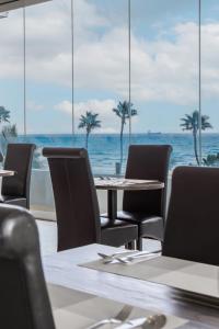 a table and chairs with the ocean in the background at Achilleos City Hotel in Larnaca