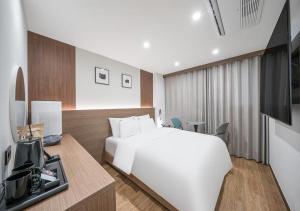 a hotel room with a white bed and a desk at Lantana Daegu Shinam Branch in Daegu