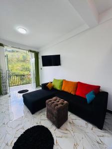 a living room with a black couch with colorful pillows at Oasis Peak Ella in Ella