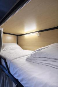 a bedroom with two white beds and a wooden headboard at Hostel Samui in Nathon Bay