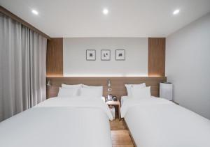 two beds in a hotel room with white sheets at Lantana Daegu Shinam Branch in Daegu