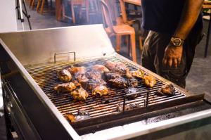a man is cooking food on a grill at Gilbys Eco Bungalow in Udaweliwitiya