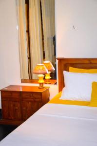 a bedroom with a bed and a table with a lamp at Gilbys Eco Bungalow in Udaweliwitiya +19 photos