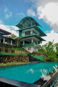 a building with a pool in front of it at Gilbys Eco Bungalow in Udaweliwitiya