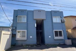 a blue house with a stairway leading up to it at シーシャイン北金沢 102号室 in Aomori