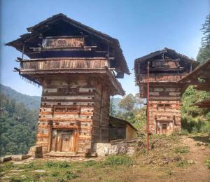 an old building on a hill with mountains in the background at Green Valley Homestay in Barkot