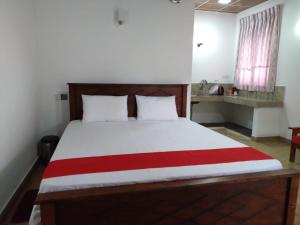 a bedroom with a bed with a red and white blanket at Lucknature Cabana Kandy in Elamalwewa
