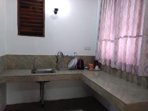 a kitchen counter with a sink and a pink curtain at Lucknature Cabana Kandy in Elamalwewa